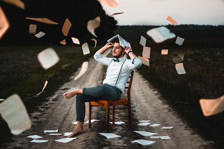 Man sitting on Chair with paper blowing around him